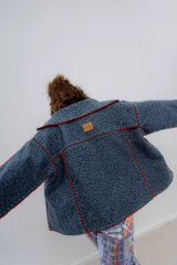 Chaqueta corta de paño de lana azul con detalles de crochet en rojo y verde.