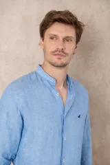 Camisa celeste de lino con cuello mao, corte slim fit, manga larga con puños abotonados y cierre frontal con botones.