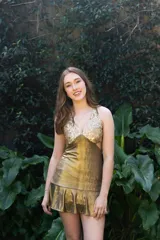 Vestido corto de lentejuelas color verde oliva, con escote en V, breteles finos cruzados en la espalda, cut-outs laterales y volado en el ruedo.