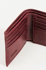 Billetera de cuero color tinto con múltiples compartimentos para tarjetas y billetes.