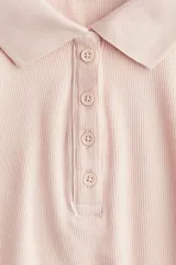 Remera polo color rosa claro, de punto acanalado, manga corta, cuello clásico y tapeta de botones.