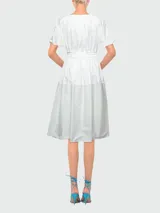 Vestido blanco de algodón con cuello redondo, mangas cortas con lazos y falda midi acampanada. Cintura ajustable con cordón.