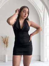 Vestido corto negro con brillos, escote halter y espalda descubierta.