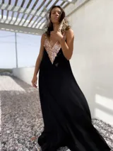 Vestido largo negro con escote en V y apliques de lentejuelas doradas en el corpiño.