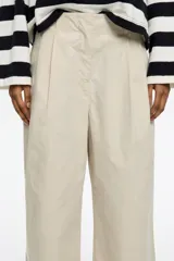 Pantalón tobillero de algodón de corte recto color rosa, con cierre frontal de corchete oculto y cremallera, pinzas en la parte delantera y presillas de tela. Presenta bolsillos diagonales delanteros y bolsillos traseros con vivo.