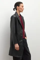 Blazer de mujer color negro, confeccionado en eco cuero, con solapas anchas, cierre frontal de un solo botón y pespuntes visibles.