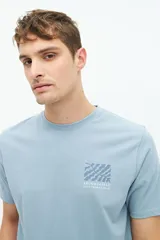 Remera blanca de algodón con estampado de recuadros con motivos botánicos en tonos grises y beige en la espalda.