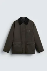 Parka relaxed fit color verde oscuro confeccionada en tejido de algodón con acabado encerado. Tiene cuello solapa combinado en pana negra, manga larga acabada en puño ajustable con botón a presión, bolsillos frontales de plastrón con solapa y detalle de bolsillo interior. Cierre frontal de botonadura oculta por solapa.