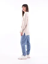 Saco color beige de tejido de punto, con cuello abierto, bolsillos frontales y mangas largas con detalle de botones en los puños.