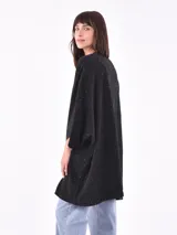 Saco negro con pequeños detalles blancos, de corte holgado y mangas 3/4.