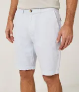 Bermuda de hombre en lino color gris claro, de corte recto, con textura discreta, bolsillos laterales y cierre frontal con botón y cremallera.