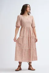 Vestido midi con estampado a cuadros color terracota y crudo, escote en V y mangas abullonadas cortas. Tiene corte imperio y falda escalonada.