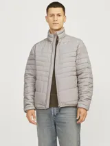 Campera puffer gris de poliéster, con cuello alto, cierre frontal con cremallera, bolsillos laterales y puños elásticos.