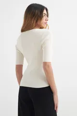 Sweater de punto color beige con rayas horizontales en naranja y blanco, de mangas cortas y cuello redondo.