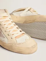 Zapatillas de media caña Golden Goose modelo Mid Star, color blanco con detalles en beige y gris. Presentan una estrella de gamuza rosada en el lateral, perforaciones decorativas y efecto desgastado en la suela.