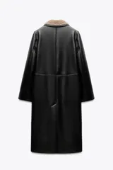 Abrigo largo de Zara Woman Collection, confeccionado en tejido efecto piel color negro. Tiene cuello solapa, manga larga, bolsillos laterales ocultos y forro interior de borreguillo color beige. El cierre es cruzado con botones.