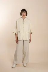 Capa color crudo de lana fina sin teñir, con capucha, cierre frontal y bolsillos con cierre.