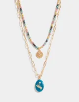 Collar corto dorado de doble cadena, una de eslabones y otra de cuentas de colores. Incluye un dije dorado con forma de sol y un dije azul con una figura grabada.