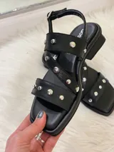 Sandalias negras de cuero sintético con tiras cruzadas y apliques de tachas plateadas.