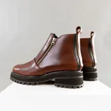 Bota de cuero vacuno color marrón, con interior forrado en corderito natural. Tiene suela de goma artesanal, punta cuadrada, cierre YKK en ambos lados y caña de 11cm.