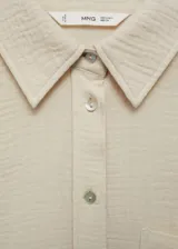 Camisa color crema de bambula con cuello camisero, diseño oversize, manga larga con puños abotonados, bolsillo de parche en la parte delantera y cierre delantero con botones.