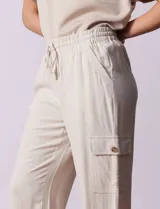 Pantalón cargo de lino color blanco, marca Marissa Olivia. Tiene pretina ancha elastizada con lazo de ajuste, bolsillos inclinados delanteros y bolsillos laterales con botón.