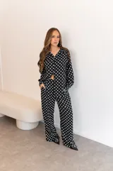Camisa negra con estampado de lunares blancos, de manga larga y cuello clásico.