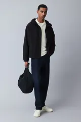 Campera rompevientos negra de nylon repelente al agua con protección UV, corte regular, cierre frontal, capucha con cordón de ajuste elástico, puños elásticos, bolsillos laterales y bolsillo interior con cierre, forro de malla y cordón de ajuste elástico oculto en el bajo.
