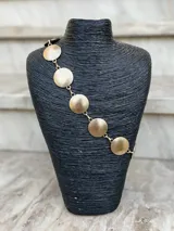 Cinto dorado de metal con eslabones y monedas circulares texturadas.