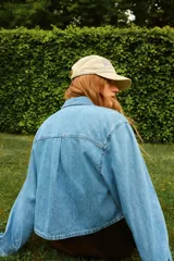 Camisa corta de denim celeste, con cuello americano, botonadura frontal, mangas largas con puños abotonados, bolsillo de parche en el pecho y bajo recto.