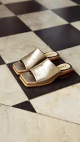 Sandalias doradas de cuero con base cuadrada y taco bajo.