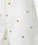Short mom de cintura alta confeccionado en jeans color crudo, con bordado de corazones metalizados dorados, trabillas en la cintura, cierre tradicional y cinco bolsillos.