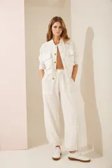 Chaqueta bomber color beige con cuello mao, cierre frontal con botones dorados, bolsillos de parche con solapa y bordado en el pecho. Puños y cintura elastizados.