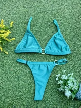 Bikini de dos piezas color celeste metalizado, compuesto por un corpiño triangular con argolla central de zamak y una bombacha colaless con argollas ajustables en los laterales. Incluye copas soft removibles.