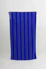 Toalla de playa de algodón con rayas verticales azules y blancas.