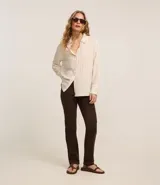 Pantalón slim de jeans color marrón, con cintura media, cierre tradicional con cremallera y botón, trabillas en la cintura, bolsillos delanteros y traseros con encaje.