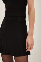 Minifalda negra tejida con cintura ancha elastizada y diseño plisado que genera movimiento.