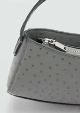 Bolso tipo baguette color gris con textura tipo piel de avestruz, asa corta y cierre de cremallera.