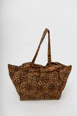 Bolso tote grande con estampado animal print de leopardo en tonos marrones y negros. Tiene doble asa de hombro y un parche con el logo de la marca en el frente.
