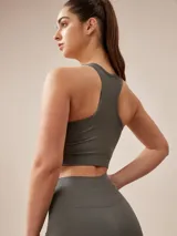Top deportivo gris oscuro con espalda deportiva y banda elástica en el bajo busto.