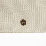 Bolso bandolera de lona color beige con detalles en cuero marrón. Tiene correa larga ajustable y cierre con hebilla dorada.