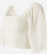 Blusa cropped color blanco, con escote recto, mangas amplias con elástico en los hombros, lastex en el cuerpo y textura.