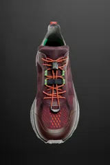 Zapatilla deportiva para carreras de montaña color borgoña con detalles en naranja y verde. Parte superior fabricada en tejido de punto transpirable con puntera y talón recubiertos de material Shield Protect Max. Ajuste de cordones mediante pieza técnica y suela con tecnología Spume Foam.
