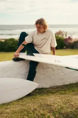 Remerón color crudo con estampa marrón en la espalda con el texto "Glassy Waves Surf Co.".