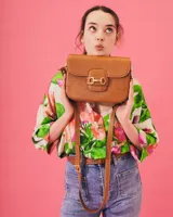 Bandolera color beige con textura símil reptil, cierre con broche metálico dorado y correa larga regulable.