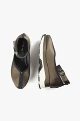Zapato color marrón con base deportiva, pulsera al tobillo ajustable con hebilla metálica y puntera redondeada.