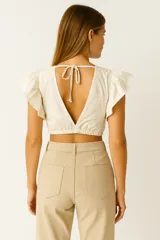 Top color crudo de viscosa, con escote en V, mangas cortas con volados y detalle de nudo en el centro.