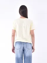 Remera de manga corta color amarillo pálido, con cuello redondo y pequeños bordados de cerezas rojas distribuidos por toda la prenda.