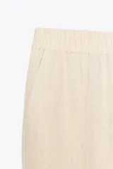 Pantalón bombacho color beige de lino, con cintura elástica, bolsillos frontales y bolsillos de parche en la espalda.