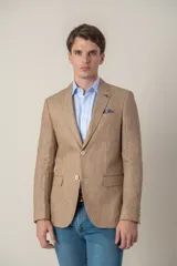 Saco de vestir color beige confeccionado en lino, de corte slim fit, con solapa de muesca, dos botones frontales, dos bolsillos delanteros con solapa y un bolsillo en el pecho. Incluye forro interno.